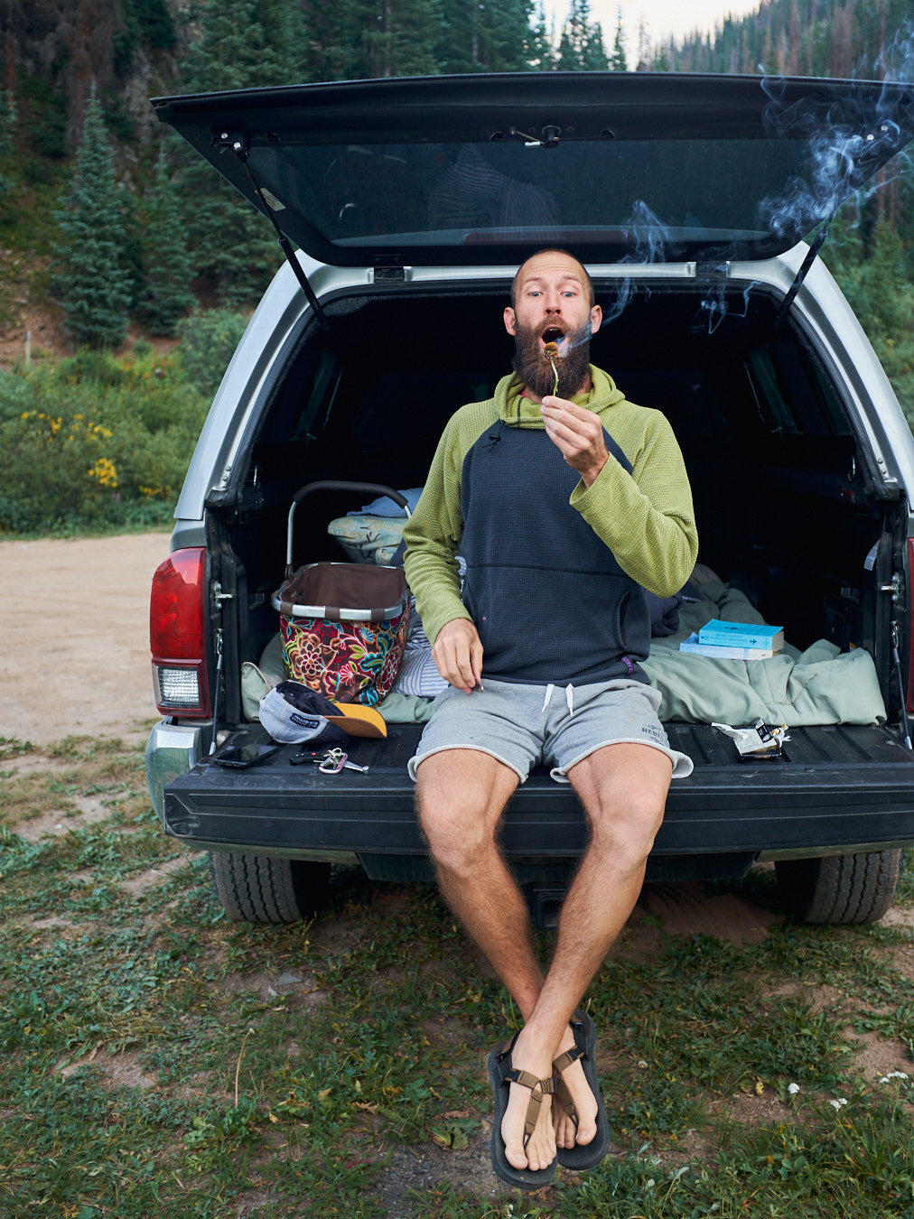A man sitting on a truck bed blowing a candle out.