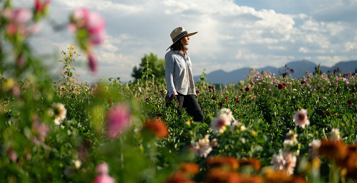 Helen is a flower farmer in Denver Colorado and she is standing in her fields of organic flowers with mountains in the background.
